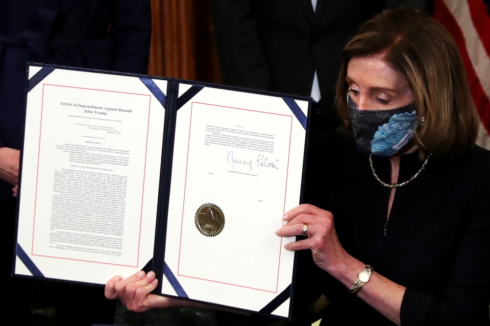US House Speaker Nancy Pelosi (D-CA) shows the article of impeachment against US President Donald Trump after signing it in an engrossment ceremony, at the US Capitol in Washington January 13, 2021. Reuters/Leah Millis 