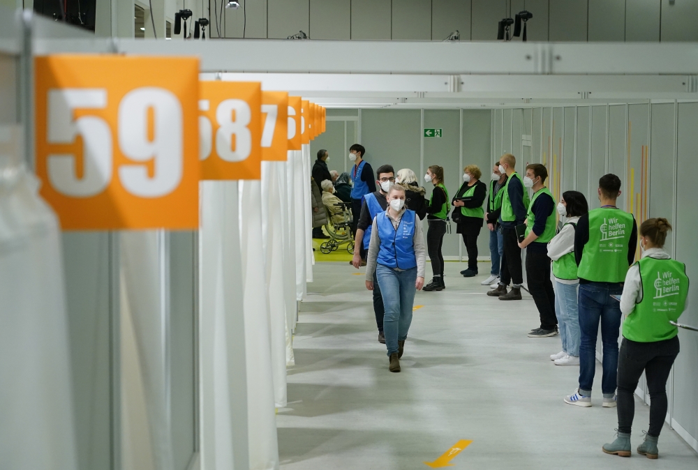 Vaccine center workers stand near cabins being used to inoculate people against the coronavirus disease (COVID-19) on the opening day of a vaccination center at the Messe Berlin trade fair grounds in Berlin, Germany January 18, 2021. Sean Gallup/Pool via 