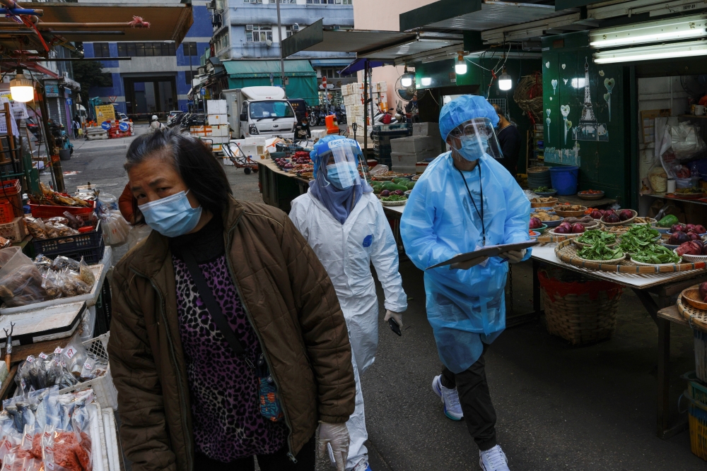 Medical workers in protective suits walk near the residential area at Jordan, after the expand of mandatory coronavirus disease (COVID-19) testing, in Hong Kong, China January 19, 2021. REUTERS/Tyrone Siu