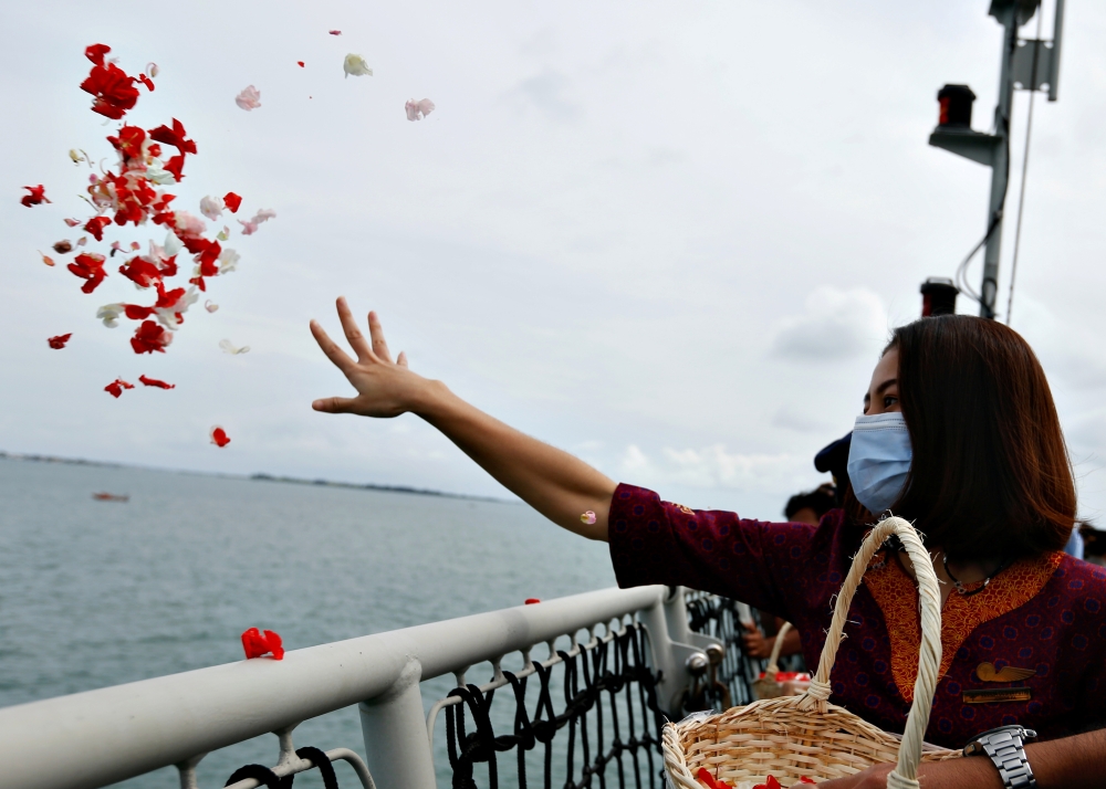 A colleague of the crew of Sriwijaya Air flight SJ 182, which crashed into the sea, throws flowers and petals from the deck of Indonesia's Naval ship KRI Semarang as they visit the site of the crash to pay their tribute, at the sea off the Jakarta coast, 