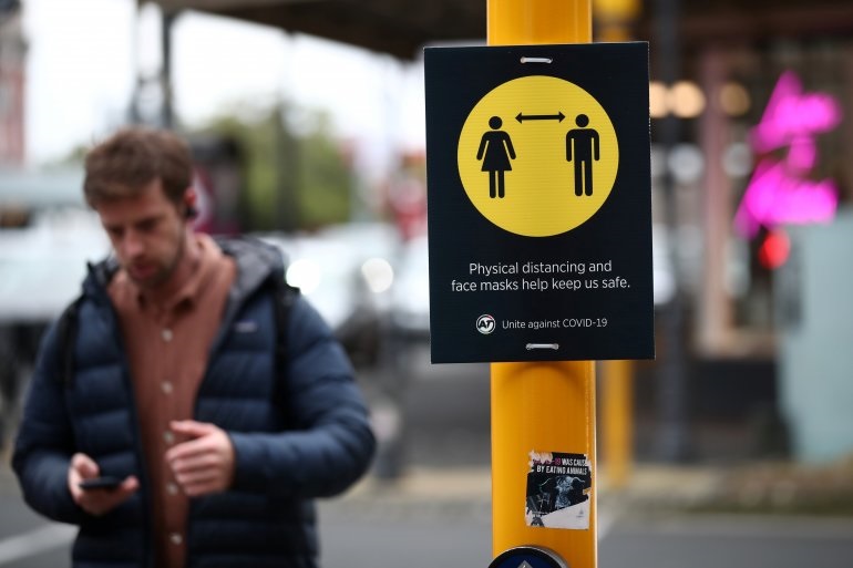 A man walks by a social distancing sign on the first day of New Zealand's new coronavirus disease (COVID-19) safety measure that mandates wearing of a mask on public transport, in Auckland, New Zealand, August 31, 2020. REUTERS/Fiona Goodall
