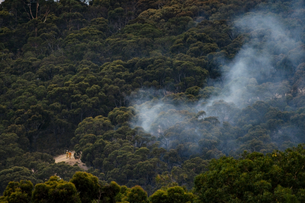Emergency services can be seen fighting a bushfire that is burning in the Cherry Gardens area in the Adelaide Hills, Australia, January 25, 2021. AAP Image/Morgan Sette/via REUTERS