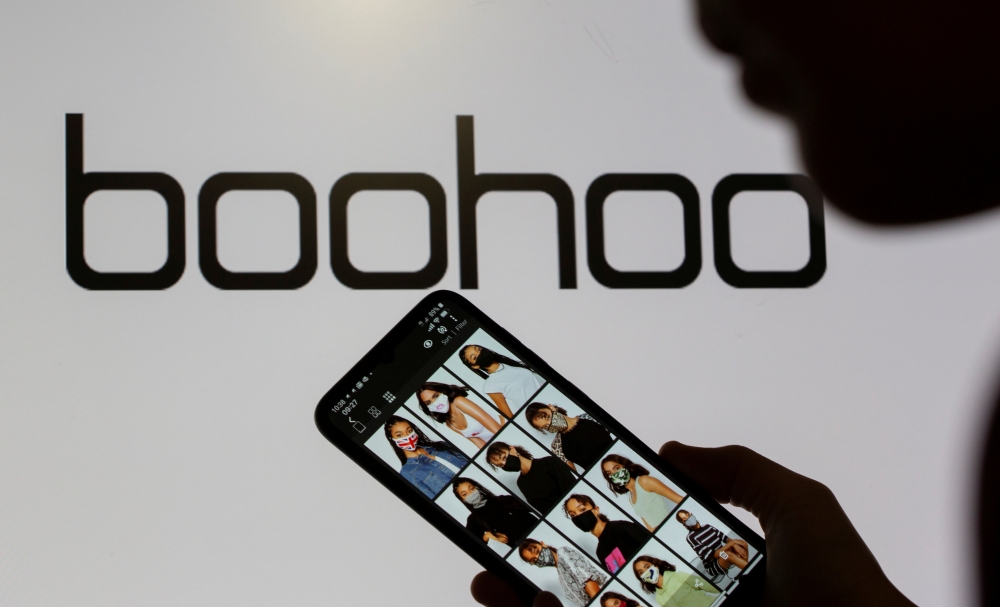 File photo: A woman poses with a smartphone showing the Boohoo app in front of the Boohoo logo in this illustration taken September 30, 2020. Reuters/Dado Ruvic/Illustration/File Photo