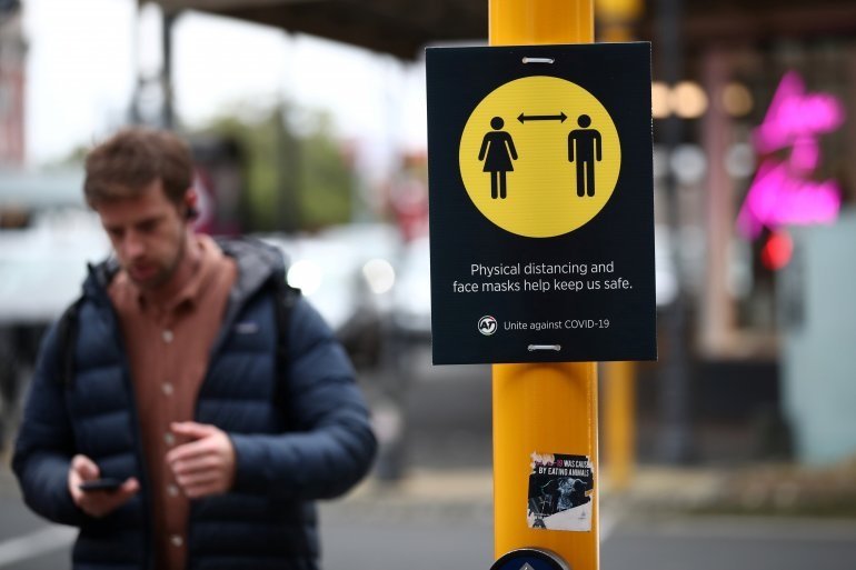 A man walks by a social distancing sign on the first day of New Zealand's new coronavirus disease (COVID-19) safety measure that mandates wearing of a mask on public transport, in Auckland, New Zealand, August 31, 2020. REUTERS/Fiona Goodall