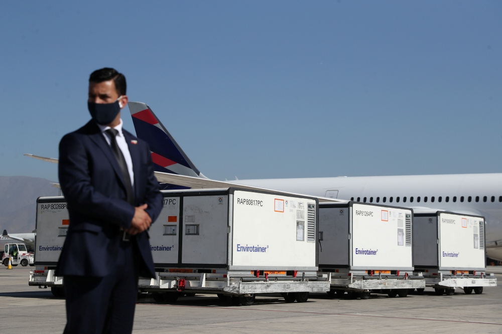 A plainclothes police stands guard next to containers transporting the first batch of the Sinovac's COVID-19 vaccine at the International airport of Santiago, as the coronavirus disease (COVID-19) outbreak continues, Chile, January 28, 2021. REUTERS/Ivan 