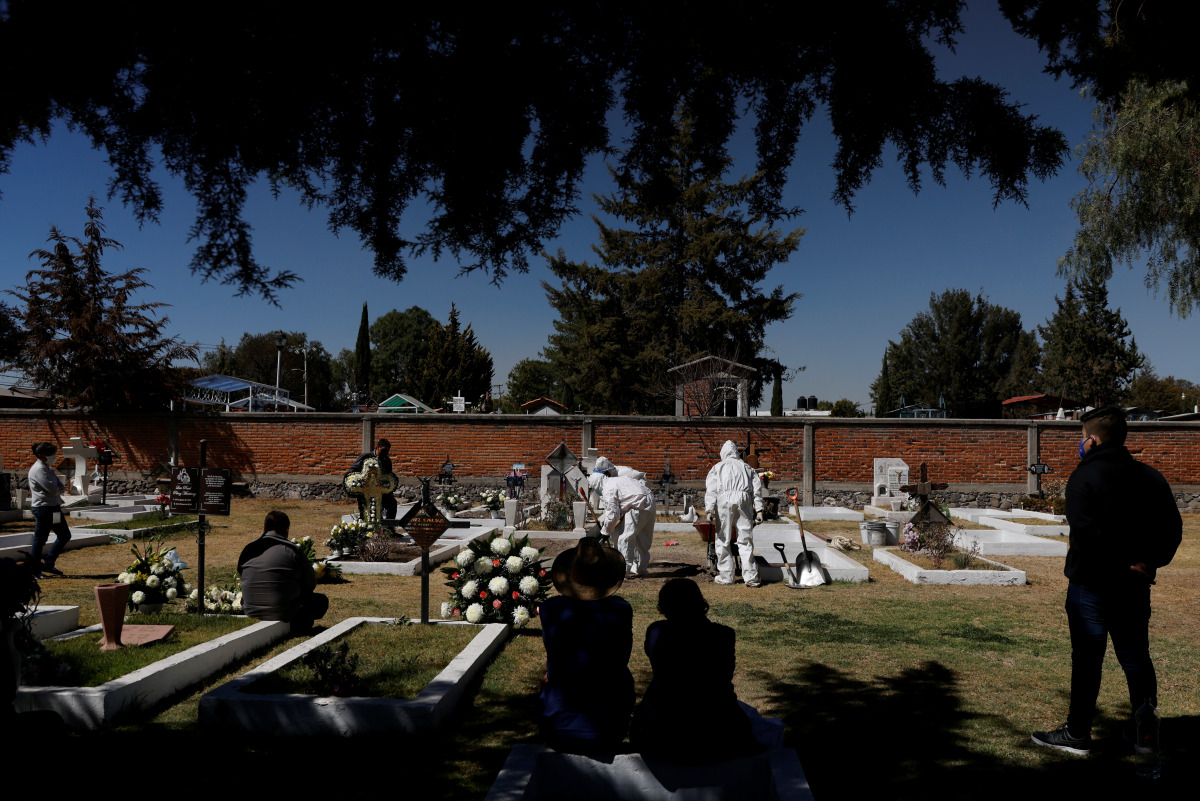 Family members look as cemetery workers bury the body, who died from the coronavirus disease (COVID-19), on the outskirts of Mexico City, Mexico January 25, 2021. REUTERS/Carlos Jasso
