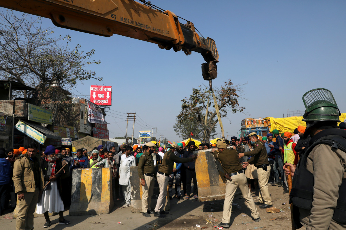 Police officers, with the help of a crane, put a barricade at the site of a protest where farmers are protesting against farm laws, at Singhu border, in New Delhi, India, January 27, 2021. REUTERS/Anushree Fadnavis
