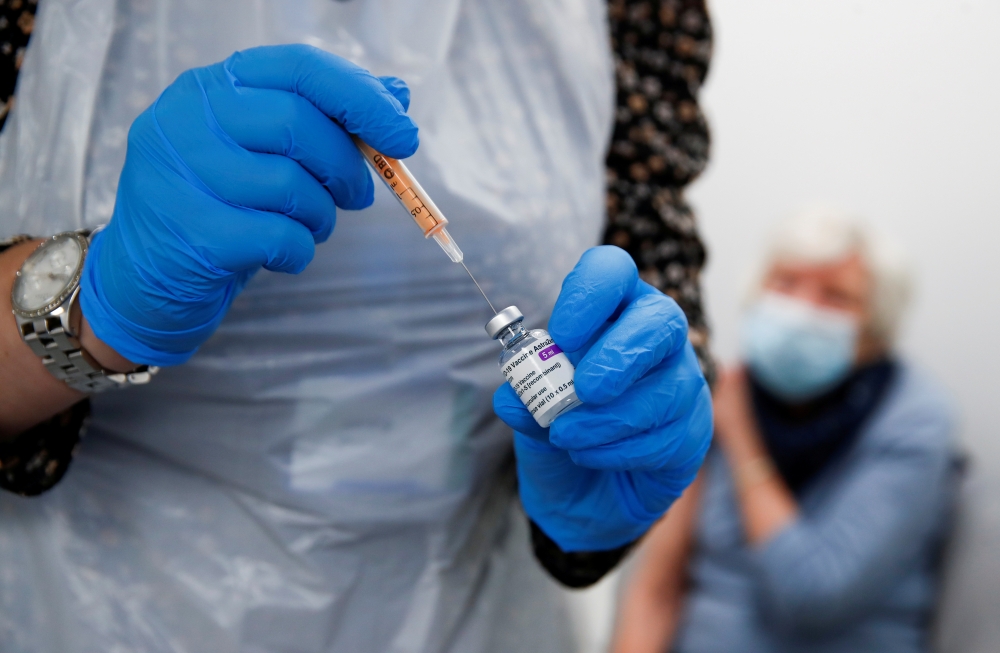 FILE PHOTO: A health worker fills a syringe with a dose of the Oxford/AstraZeneca COVID-19 vaccine at the Appleton Village Pharmacy, amid the coronavirus disease (COVID-19) outbreak, in Widnes, Britain January 14, 2021. REUTERS/Jason Cairnduff