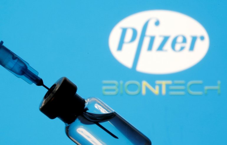 A vial and syringe are seen in front of a displayed Pfizer and Biontech logo in this illustration taken January 11, 2021. REUTERS/Dado Ruvic/Illustration
