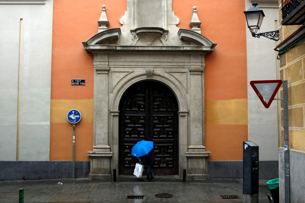A man shelters from the rain underneath a blue umbrella during the coronavirus disease (COVID-19) outbreak in Madrid, Spain, February 2, 2021. REUTERS/Susana Vera