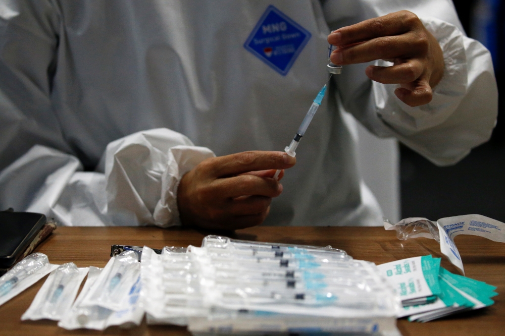A healthcare worker prepares a dose of Sinovac's vaccine for the coronavirus disease (COVID-19) during a mass vaccination for medical workers at the Istora Senayan stadium in Jakarta, Indonesia, February 4, 2021. REUTERS/Willy Kurniawan