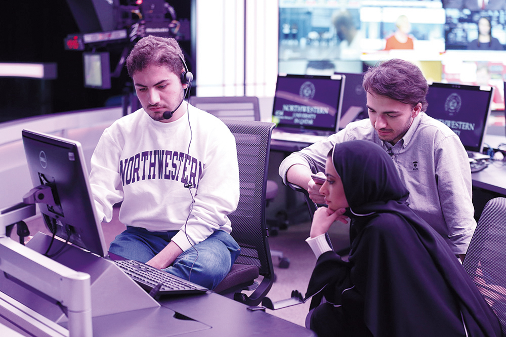 Northwestern Qatar students Ayman Al Rashid (left), Muaaz Dembinski, and Jawaher AlMoawda working together in the Newsroom, where journalism students learn to report and produce news shows.