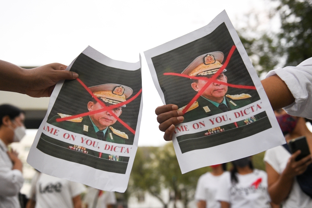 People hold pictures of Myanmar's army chief Min Aung Hlaing with his face crossed out as Myanmar citizens protest against the military coup in Myanmar outside United Nations venue in Bangkok, Thailand February 6, 2021. REUTERS/Chalinee Thirasupa