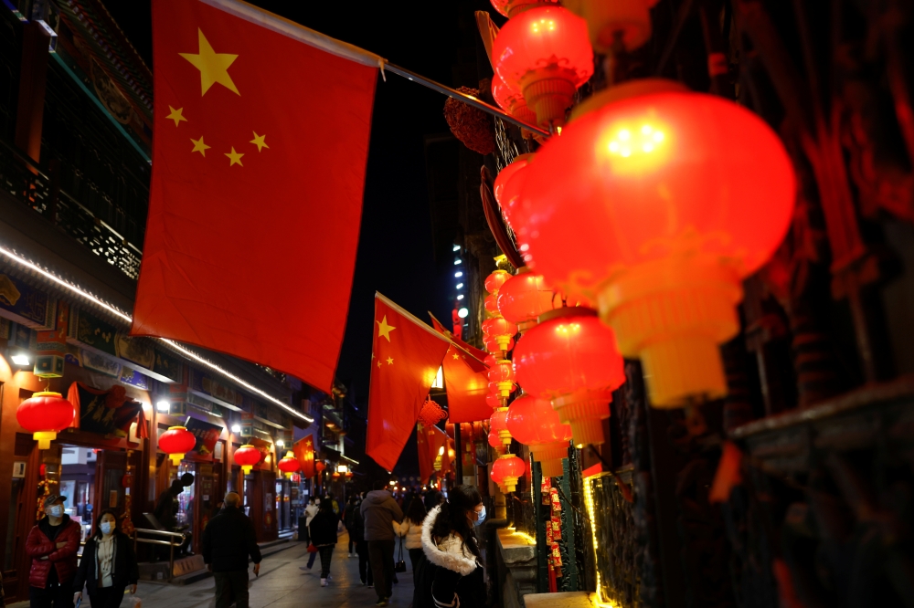 People wearing face masks following an outbreak of the coronavirus disease (COVID-19) walk near the Qianmen street ahead of Lunar New Year celebrations, in Beijing, China February 10, 2021. REUTERS/Carlos Garcia Rawlins

