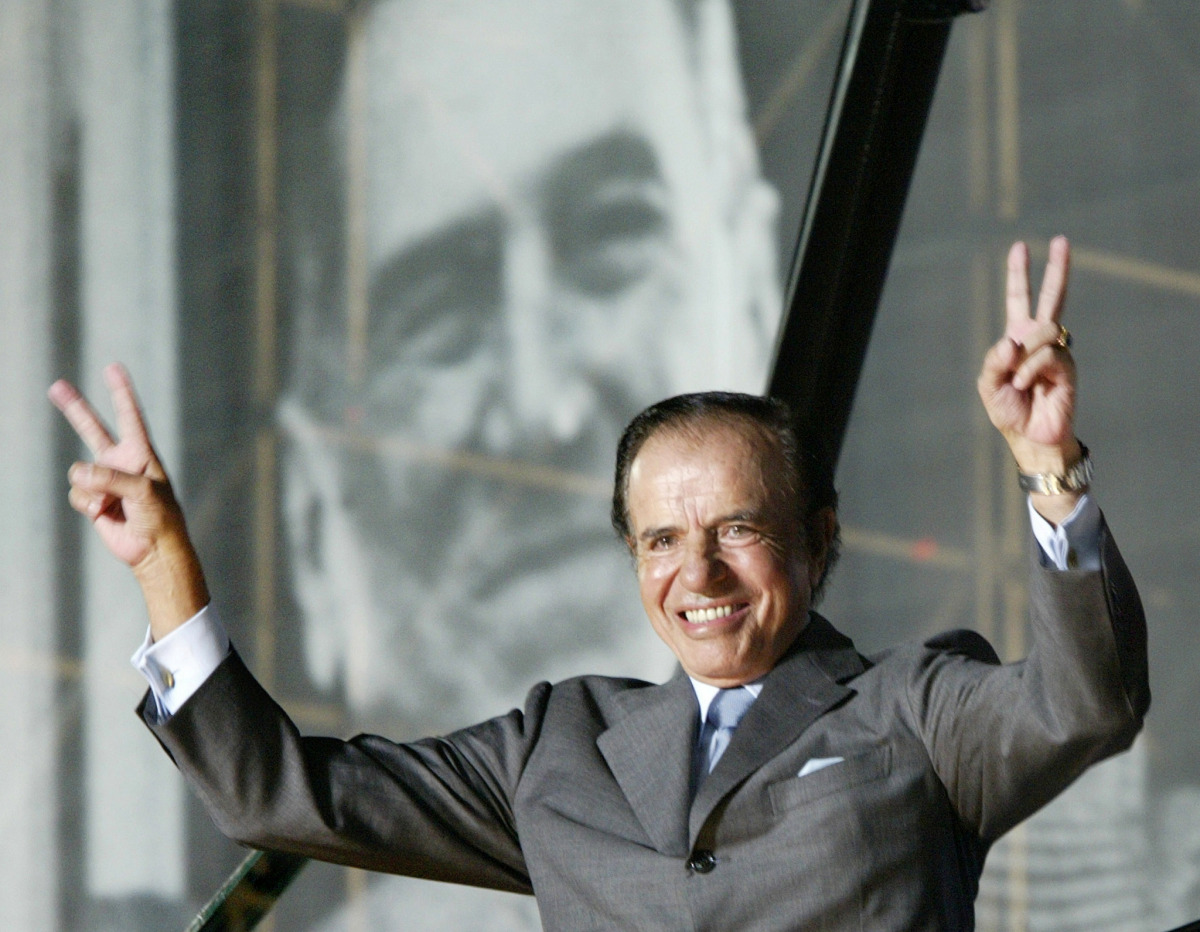 FILE PHOTO: Argentine presidential candidate Carlos Menem stands in front of a giant poster of former President Juan Domingo Peron, as he waves to thousands of followers in River Plate Stadium during the final rally of his campaign, in Buenos Aires, April