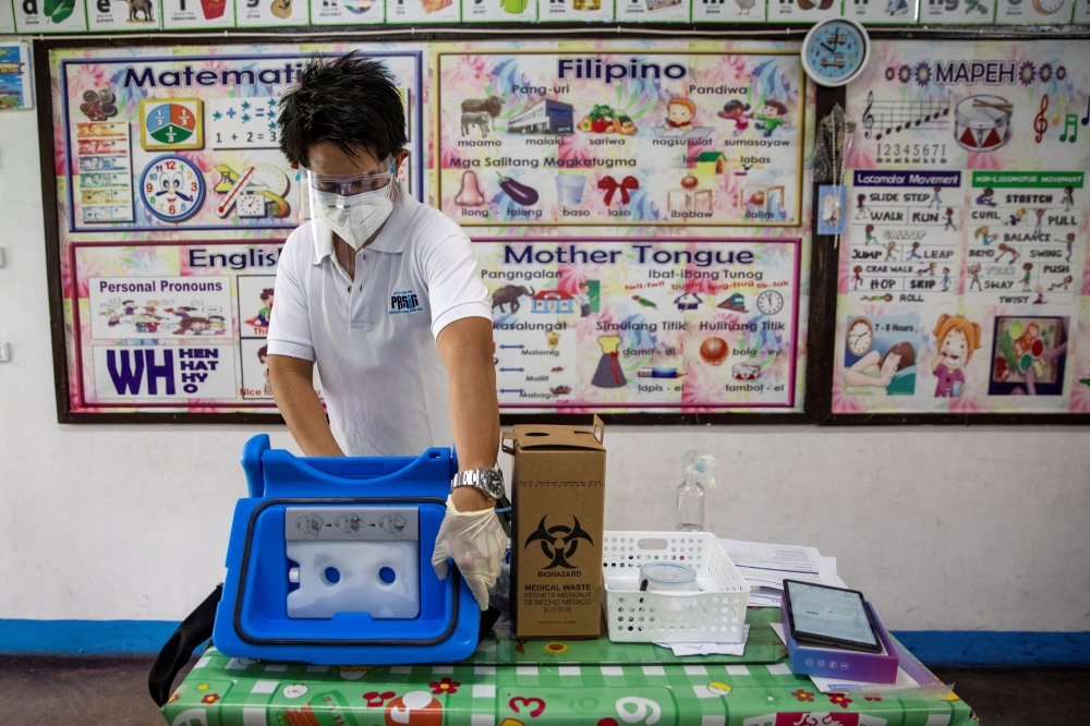 A health worker opens a box containing mock COVID-19 vaccines during a simulation in preparation for its arrival, at an elementary school turned vaccination command center in Pasig City, Metro Manila, Philippines, February 16, 2021. REUTERS/Eloisa Lopez/F
