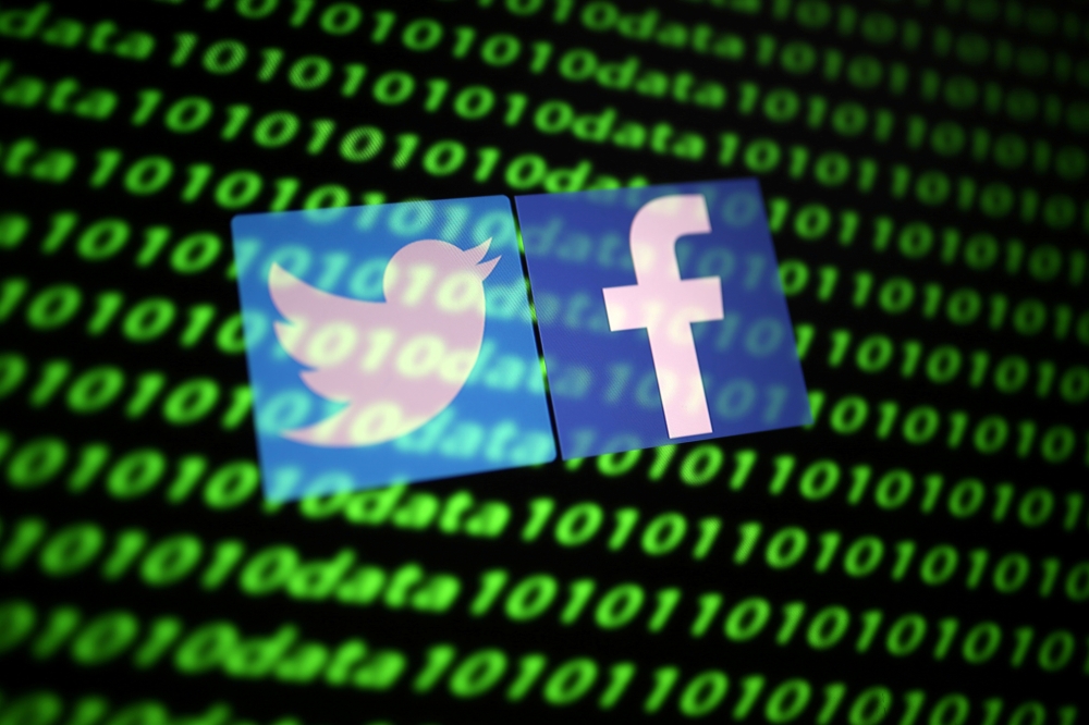 The Twitter and Facebook logo along with binary cyber codes are seen in this illustration taken November 26, 2019. REUTERS/Dado Ruvic/Illustration/File Photo