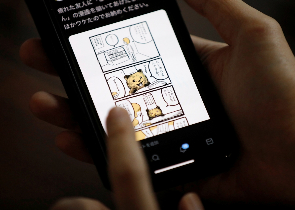 Japanese manga artist Kamentotsu shows his his four-panel strip comic 'Koguma's Cake Shop' on his smartphone at his workspace in Tokyo, Japan October 8, 2020. Picture taken October 8, 2020. REUTERS/Issei Kato
