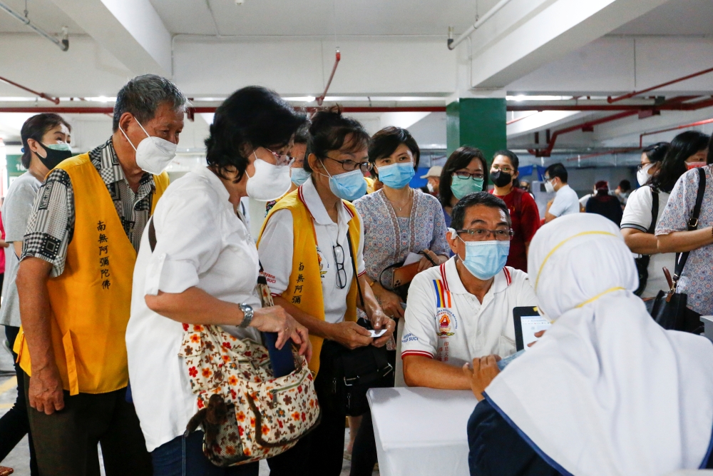 People talk to the officials before receiving the first dose of China's Sinovac Biotech vaccine for the coronavirus disease (COVID-19) during the mass vaccination program for clergy at the parking lot of Grand Istiqlal Mosque in Jakarta, Indonesia, Februa