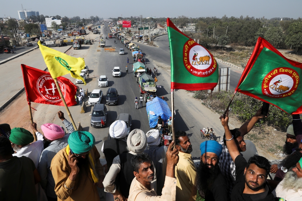 Farmers cheer and wave flags as more tractors arrive from Punjab to participate in the ongoing farmers' protest at Singhu border, to mark 100th day of demonstrations against the farm laws, near Kundli border, in Haryana India, March 6, 2021. REUTERS/Anush