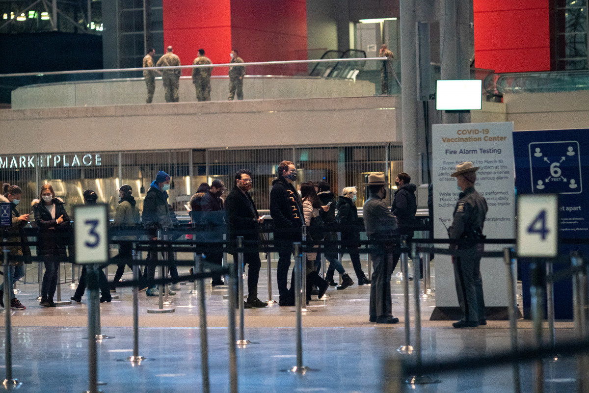 People wait in a line stretching inside the Jacob K. Javits Convention Center on midtown Manhattan's west side, to receive a dose of the coronavirus disease (COVID-19) vaccine at the site which has been converted into a mass vaccination center in New York