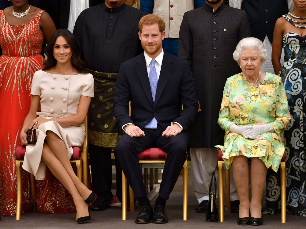 FILE PHOTO: Britain's Queen Elizabeth, Prince Harry and Meghan, the Duchess of Sussex pose for a picture with some of Queen's Young Leaders at a Buckingham Palace reception following the final Queen's Young Leaders Awards Ceremony, in London, Britain June