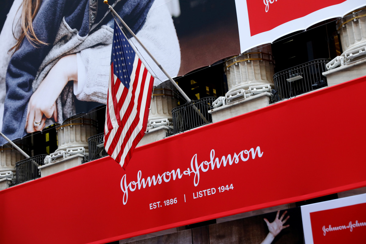 FILE PHOTO: The U.S. flag is seen over the company logo for Johnson & Johnson to celebrate the 75th anniversary of the company's listing at the New York Stock Exchange (NYSE) in New York, U.S., September 17, 2019. REUTERS/Brendan McDermid/File Photo
