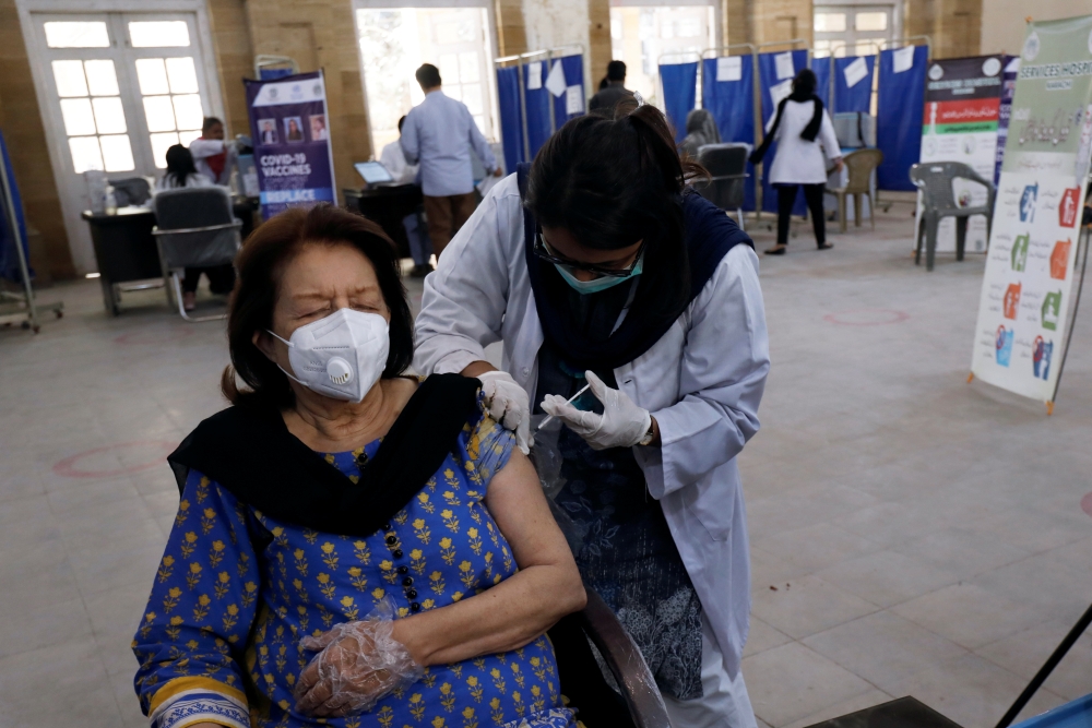 A woman receives the first dose of the coronavirus disease (COVID-19) vaccine, as the government started vaccination for the general public, starting with elderly people, at a vaccination center in Karachi, Pakistan March 10, 2021. REUTERS/Akhtar Soomro
