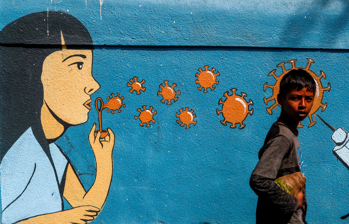 A boy walks past a graffiti amidst the spread of the coronavirus disease (COVID-19) on a street in Navi Mumbai, India, March 5, 2021. REUTERS/Francis Mascarenhas TPX IMAGES OF THE DAY
