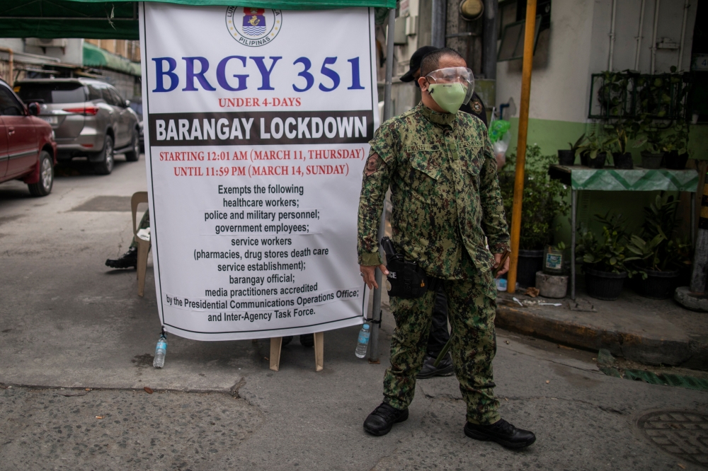 A police officer mans a checkpoint at a village under lockdown amid rising coronavirus disease (COVID-19) infections, in Manila, Philippines, March 12, 2021. REUTERS/Eloisa Lopez/File Photo