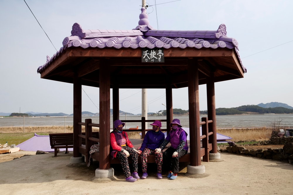 Residents dressed in purple clothing take a break at the Purple Island in Shinan, South Korea, March 9, 2021. Picture taken March 9, 2021. REUTERS/Daewoung Kim