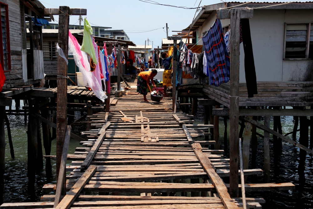 A woman washes clothes on a wooden path between stilt houses at Hanuabada Village, located in Port Moresby Harbour, Papua New Guinea, November 19, 2018. Picture taken November 19, 2018. REUTERS/David Gray/File Photo