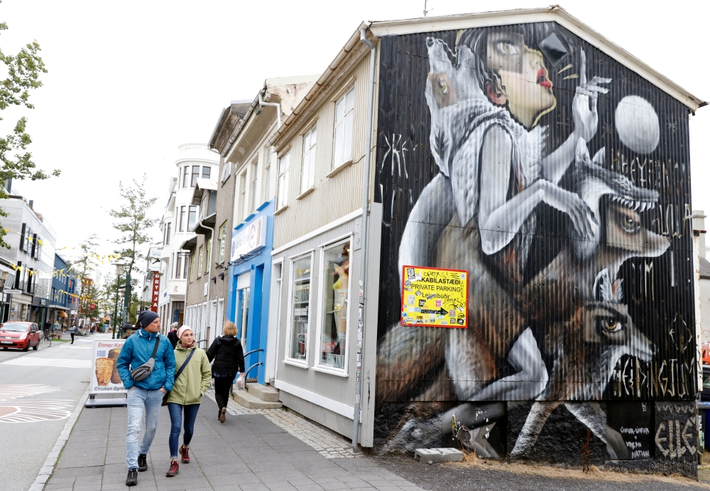People walk past artwork on the side of a shop as the outbreak of the coronavirus disease (COVID-19) continues in Reykjavik, Iceland, September 3, 2020. REUTERS/John Sibley/File Photo