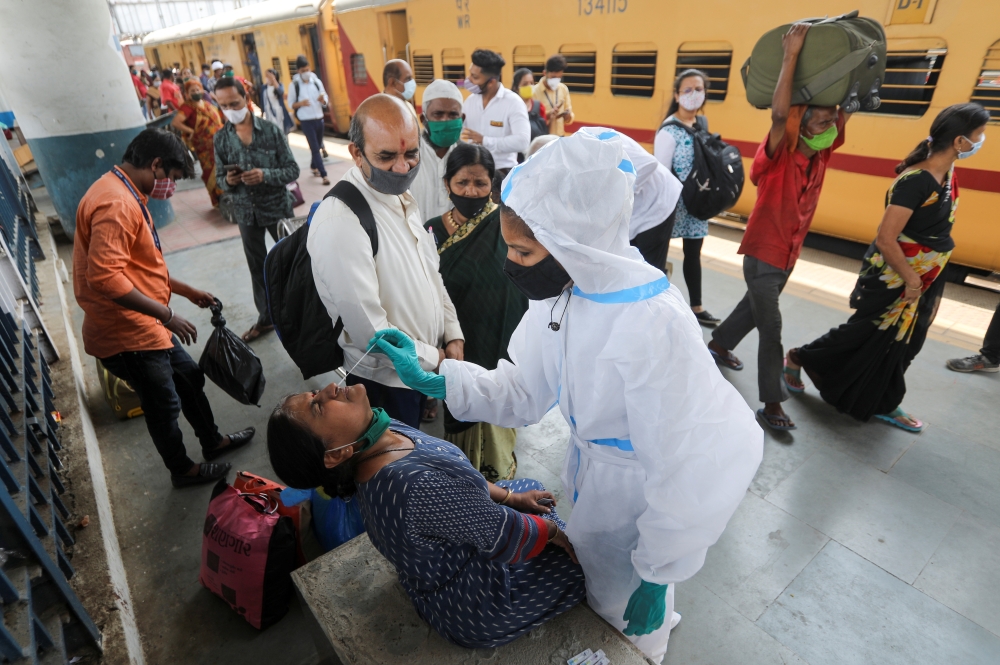 A health worker in personal protective equipment (PPE) collects a swab sample from a woman during a rapid antigen testing campaign for the coronavirus disease (COVID-19), at a railway station platform in Mumbai, India, March 17, 2021. REUTERS/Francis Masc