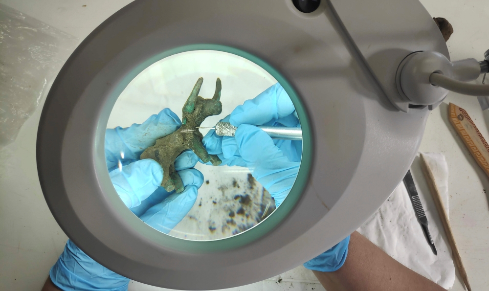 An archaeologist works on a 2,500-year-old bronze bull idol that was unearthed at the archaeological site of Olympia, Greece, February 26, 2021. Picture taken February 26, 2021. Greek Ministry of Culture/Handout via REUTERS