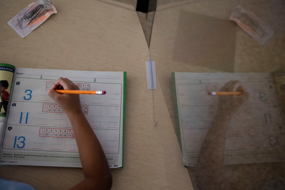 A student writes after returning to school as coronavirus disease (COVID-19) restrictions are lifted in Philadelphia, Pennsylvania, U.S., March 8, 2021. REUTERS/Hannah Beier/File Photo