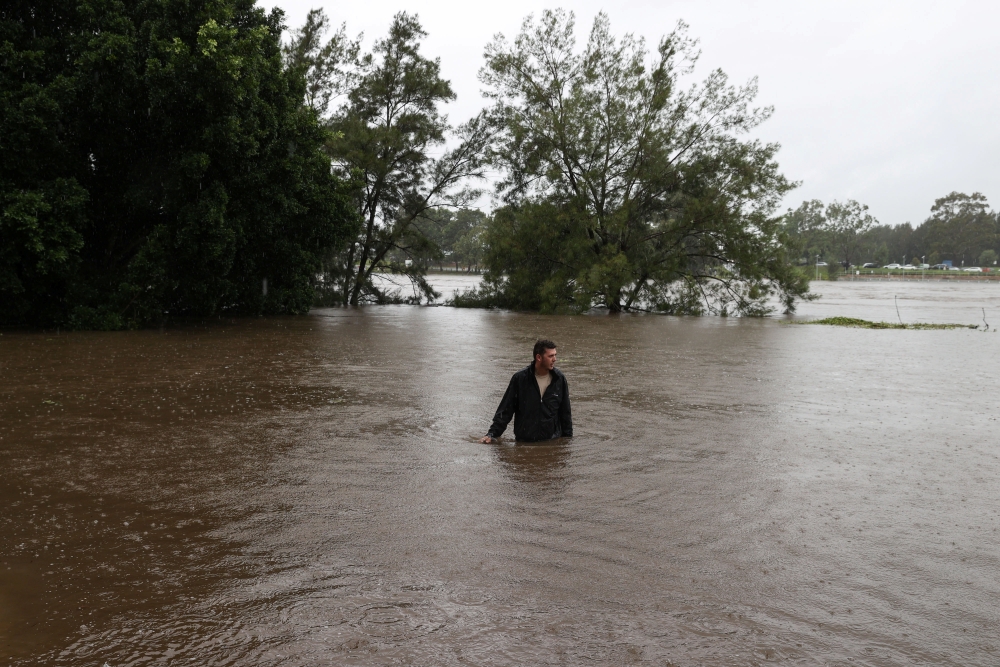 A man wades through floodwaters on a residential street near the swollen Nepean River as the state of New South Wales experiences widespread flooding and severe weather, in Sydney, Australia, March 21, 2021. REUTERS/Loren Elliott