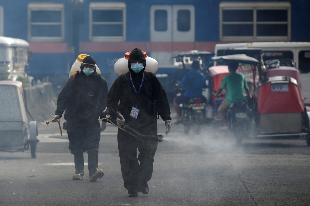 Workers in hazmat suits disinfect a street as a preventive measure against the spread of coronavirus disease (COVID-19) at a village in Manila, Philippines, March 19, 2021. REUTERS/Lisa Marie David