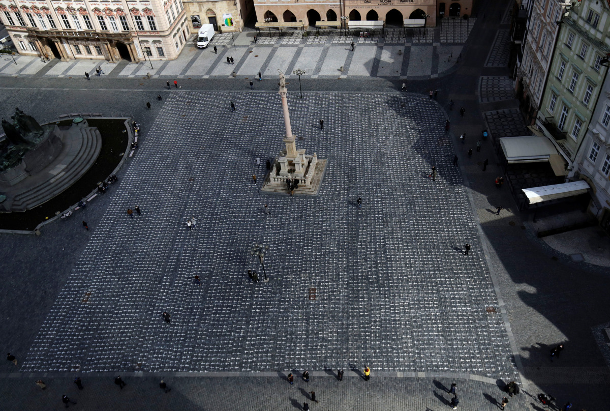 People are seen at the Old Town Square where thousands of crosses have been painted on a pavement to commemorate the first anniversary since the death of the first Czech coronavirus disease (COVID-19) patient in Prague, Czech Republic, March 22, 2021. REU