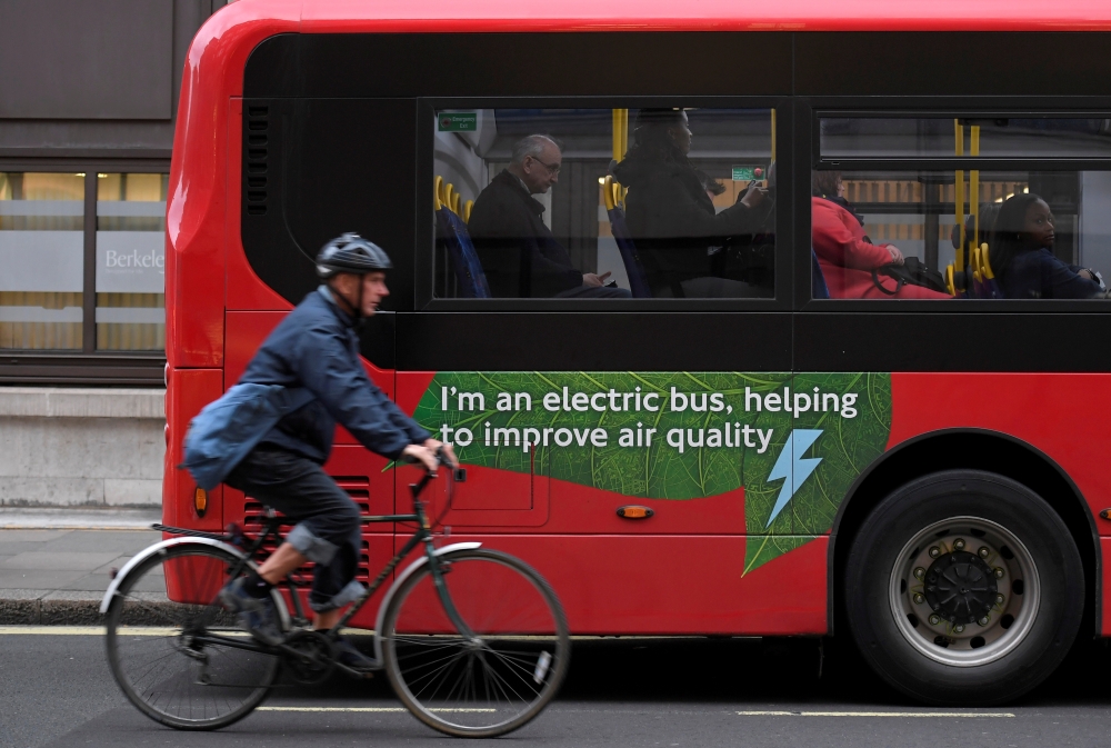 A cyclist rides past an electric public bus on the day that Mayor of London Sadiq Khan outlined plans to place a levy on the most polluting vehicles in London, Britain, April 4, 2017. REUTERS/Toby Melville/File Photo