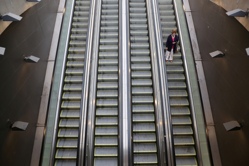 A woman uses mechanic stairs at a metro main access as local town halls have increased the lockdown restrictions during the coronavirus disease (COVID-19) outbreak, in Santiago, Chile, March 25, 2021. REUTERS/Ivan Alvarado