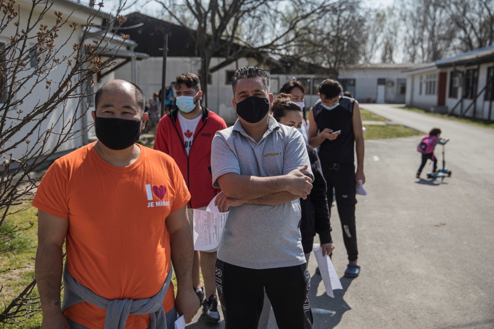 Migrants wait in line to receive the AstraZeneca vaccine against the coronavirus disease (COVID-19) at a camp for refugees and migrants in Belgrade, Serbia, March 26, 2021. REUTERS/Marko Djurica