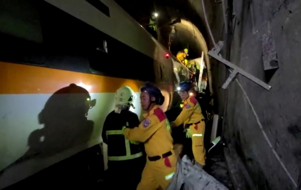 Rescue workers walk next to a damaged train which derailed in a tunnel north of Hualien, Taiwan April 2, 2021, in this still image taken from video. FTV via REUTERS ATTENTION EDITORS - THIS IMAGE WAS PROVIDED BY A THIRD PARTY. NO RESALES. NO ARCHIVES. TAI