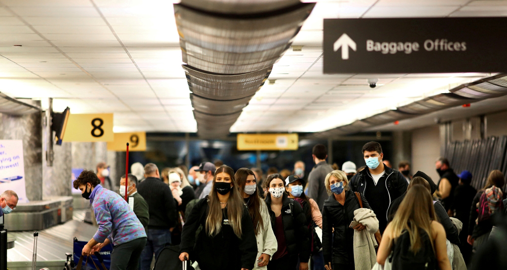 Travelers wearing protective face masks to prevent the spread of the coronavirus disease (COVID-19) reclaim their luggage at the airport in Denver, Colorado, U.S., November 24, 2020. REUTERS/Kevin Mohatt/File Photo