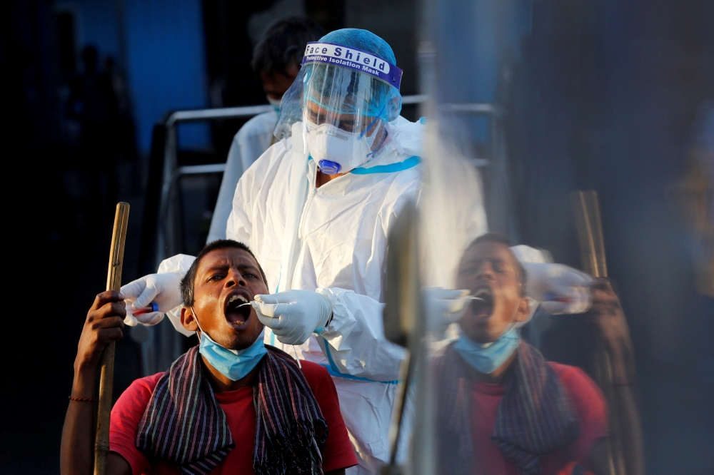 File photo: A healthcare worker collects a coronavirus disease (COVID-19) test swab sample from a man, at a temporary shelter for homeless people in New Delhi, India, March 31, 2021. Reuters/Adnan Abidi/File Photo