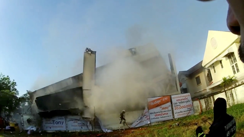 A fire brigade member runs away as three-story building collapses in Bangkok, Thailand April 3, 2021 in this still image obtained from a social media video. 
