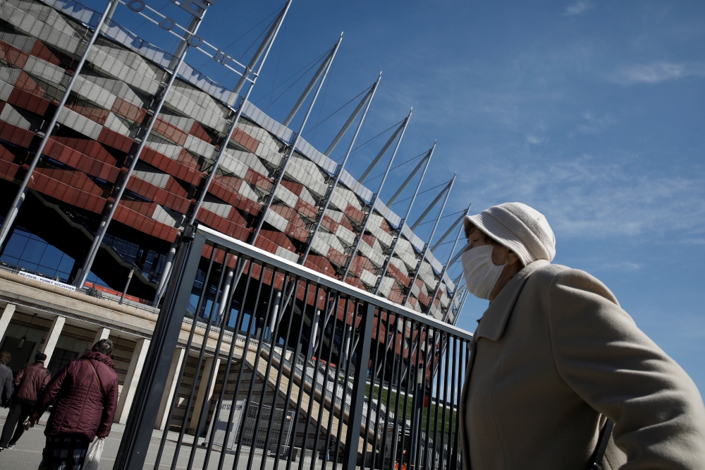A person wearing a protective mask walks towards the coronavirus disease (COVID-19) vaccination centre situated at a temporary hospital organised at the National Stadium in Warsaw, Poland April 2, 2021. Reuters/Kacper Pempel