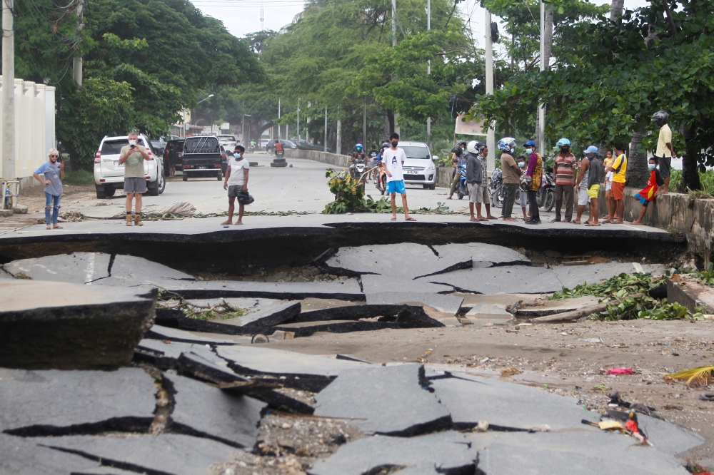 People stand near roads damaged by floods after heavy rainfall in Dili, East Timor, April 5, 2021. REUTERS/Lirio da Fonseca