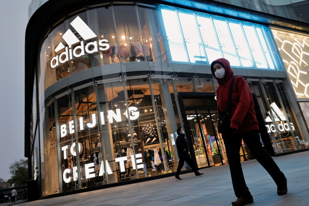 People walk past an Adidas store in a shopping district following an outbreak of the coronavirus disease (COVID-19) in Beijing, China, April 5, 2021. REUTERS/Thomas Peter