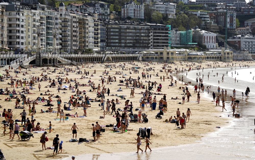 People enjoy the sun at La Concha beach after Spain introduced stricter mask laws during the coronavirus disease (COVID-19) outbreak, in San Sebastian, Spain March 31, 2021. REUTERS/Vincent West
